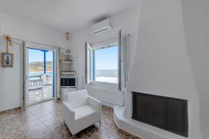 a living room with a tv and a white chair at ENDLESS BLUE from Syros - Fabrika Resort in Vári