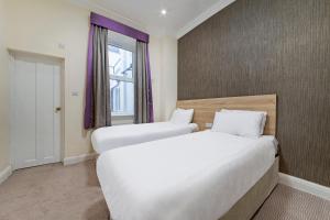 two beds in a room with a window at OYO 24 Sussex, London Paddington in London