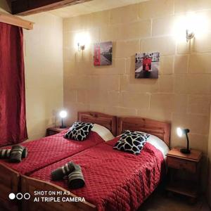 a bedroom with a red bed with two pillows at 3 bedrooms villa with private pool and wifi at Qala in Qala