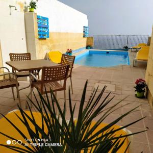 a patio with a table and chairs and a swimming pool at 3 bedrooms villa with private pool and wifi at Qala in Qala