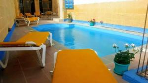 a swimming pool with two yellow benches next to it at 3 bedrooms villa with private pool and wifi at Qala in Qala