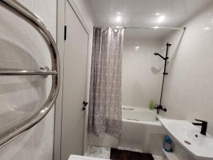 a white bathroom with a shower and a sink at Апартаменты на Титова in Dnipro