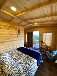 Dormitorio en cabaña de madera con cama y silla en Serás Libre Refugio, en Zipaquirá