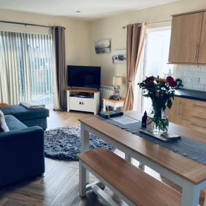 a living room with a table with a vase of flowers at Ramblers Rest Modern Cottage-Perfect Views of Ben Nevis in Fort William