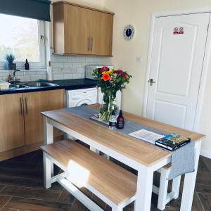 una cocina con una mesa con un jarrón de flores. en Ramblers Rest Modern Cottage-Perfect Views of Ben Nevis, en Fort William