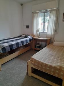 1 dormitorio con 2 camas, escritorio y ventana en Casa de descanso para 6 en Tandil en Tandil