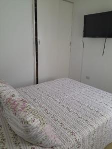 1 cama con manta blanca y TV en la pared en Casa de descanso para 6 en Tandil en Tandil