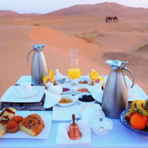 uma mesa com comida e bebidas no deserto em Deep Desert Camp em Merzouga