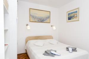 Un dormitorio blanco con una cama con dos teléfonos. en White Wave Guest House, en Dubrovnik