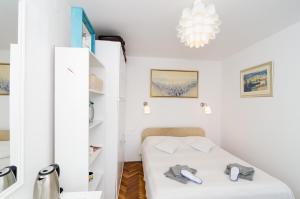 Habitación blanca pequeña con cama y lámpara de araña. en White Wave Guest House, en Dubrovnik