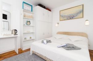 Dormitorio blanco con cama y estante en White Wave Guest House, en Dubrovnik
