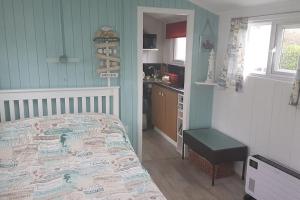 a bedroom with a bed and a kitchen in it at Captain's Cabin in Cadgwith