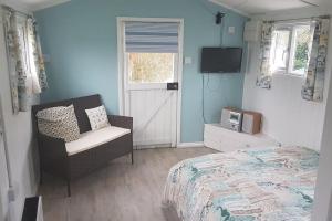 a bedroom with a bed and a chair and a television at Captain's Cabin in Cadgwith