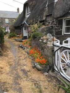 a stone house with a white fence and flowers at Captain's Cabin in Cadgwith