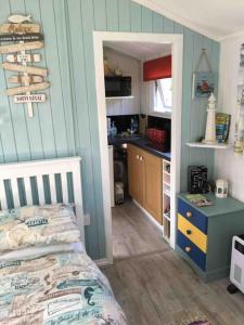 a small bedroom with a bed and a kitchen at Captain's Cabin in Cadgwith