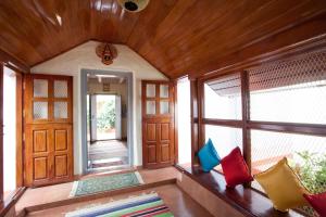 NapokluにあるSardar Bahadur's Heritage Bungalow Estate Stayの木製の壁の客室で、カラフルな枕付きのドアが備わります。