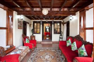 a living room with red couches and a rug at Sardar Bahadur's Heritage Bungalow Estate Stay in Napoklu
