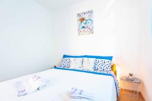 ein Schlafzimmer mit einem weißen Bett mit blauen Kissen in der Unterkunft Apartment Hannah in Novalja