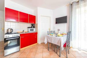 eine kleine Küche mit roten Schränken und einem Tisch mit Tischdecke in der Unterkunft Apartment Hannah in Novalja