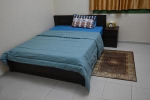 a bedroom with a bed with a blue blanket and a rug at Entire Studio Flat in Sharjah. in Sharjah