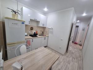 cocina con armarios blancos y suelo de madera en Посуточная квартира на Мухита c Wi-Fi, en Uralsk