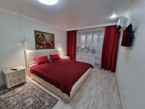- une chambre avec un lit rouge et une fenêtre dans l'établissement Посуточная квартира на Мухита c Wi-Fi, à Uralsk