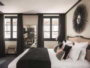 - une chambre avec un grand lit et des oreillers noirs et blancs dans l'établissement Maisons du Monde Hôtel & Suites - Marseille Vieux Port, à Marseille
