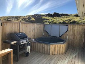 bañera de hidromasaje y parrilla en una terraza de madera en EYVÍK Cottages - Private HOT TUB!, en Selfoss