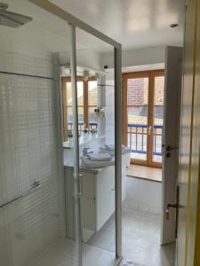 een badkamer met een douche, een wastafel en een spiegel bij Hôtel MADO in Le Crotoy
