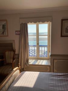 a bedroom with a window with a view of the ocean at Hôtel MADO in Le Crotoy