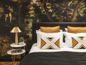 Un dormitorio con una cama con almohadas y una pintura en Maisons du Monde Hôtel & Suites - Marseille Vieux Port, en Marsella