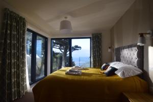 1 dormitorio con cama amarilla y ventana grande en Flat 2 High Tide House - Stylish flat with large terrace and incredible sea views, en Mortehoe