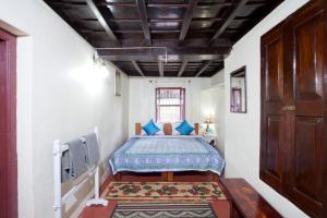 a bedroom with a bed with blue pillows at Sardar Bahadur's Heritage Bungalow Estate Stay in Napoklu
