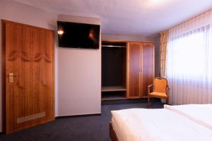 a bedroom with a bed and a television on a wall at Hotel-Restaurant Weinhaus Grebel in Koblenz