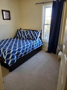 a bedroom with a bed with a blue comforter and a window at Why Not enjoy while away! in Harrisonburg