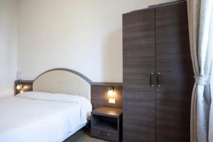 Hotel Amalfi في ميلانو: غرفة نوم بسرير أبيض وخزانة خشبية