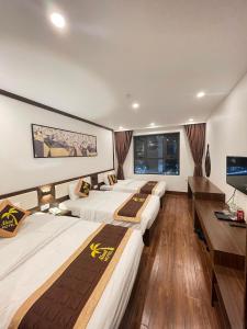 a room with four beds and a flat screen tv at Aland Hotel in Ha Long