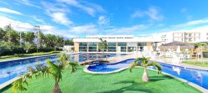 ein Swimmingpool mit Palmen vor einem Gebäude in der Unterkunft Muro Alto Condomínio Clube in Porto De Galinhas