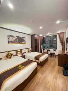 a hotel room with two beds and a desk at Aland Hotel in Ha Long