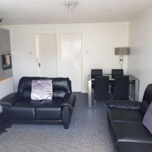 a living room with a black leather couch and a table at 127 - 2 Bed Deluxe Chalet, Belle Aire, Beach Road, Hemsby, Norfolk, NR29 4HZ in Hemsby