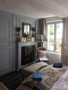 um quarto com uma cama, uma lareira e uma cadeira em Maison de village sur la route du cidre em Cambremer