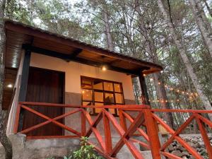a small cabin in the woods with a red fence at Cotan Ecolodge in La Esperanza
