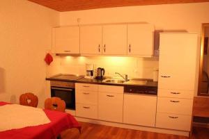 a kitchen with white cabinets and a sink and a bed at Ferienwohnung-Feldberg-in-der-Pension-Gloecklehof in Todtnau