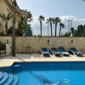 einen Pool mit blauen Stühlen neben einer Wand in der Unterkunft Beautiful villa 2 steps from the BEACH in Marbella