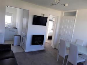 a living room with a fireplace and a tv on the wall at Fabulous 2 bedroom dog friendly chalet 5 min walk to beach, nr Gt Yarmouth & Norfolk Broads in Scratby