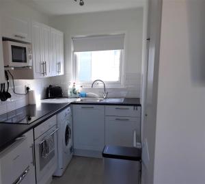 a white kitchen with a sink and a dishwasher at Fabulous 2 bedroom dog friendly chalet 5 min walk to beach, nr Gt Yarmouth & Norfolk Broads in Scratby