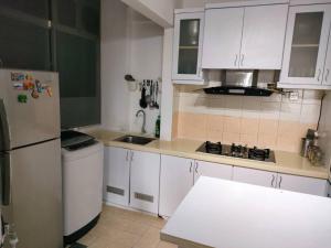 a kitchen with white cabinets and a white refrigerator at Permai Puteri Homestay Ampang in Ampang