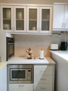 a kitchen with white cabinets and a microwave at Permai Puteri Homestay Ampang in Ampang