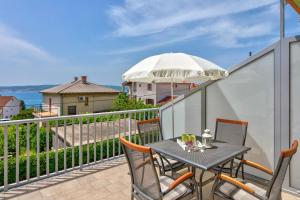 a table and chairs on a balcony with an umbrella at Apartments Jasna in Crikvenica