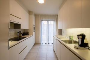 una cucina con armadi bianchi e una grande finestra di Appartement GT a Blankenberge